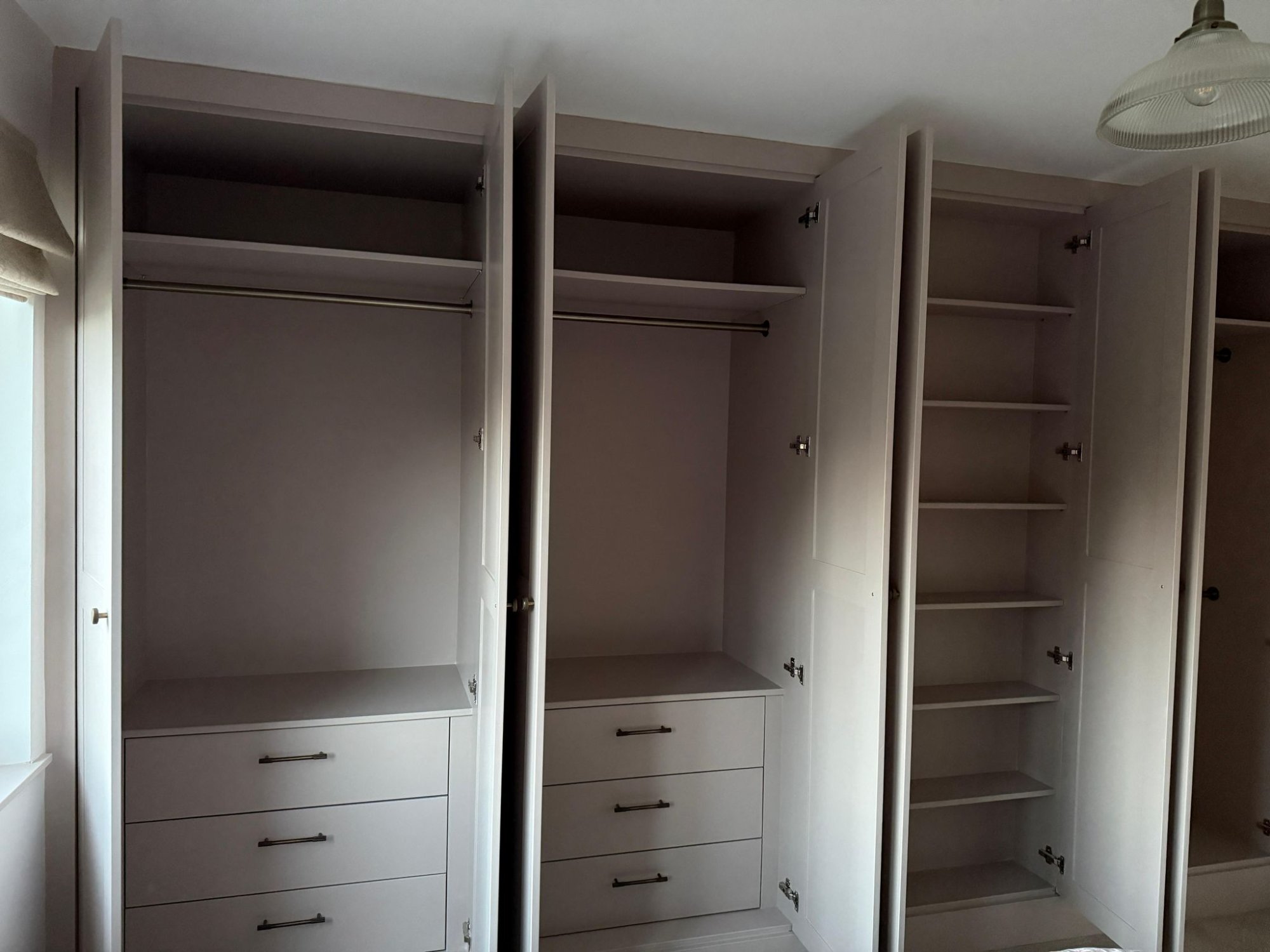 Full wall wardrobe open showing drawers, rails, and shelving