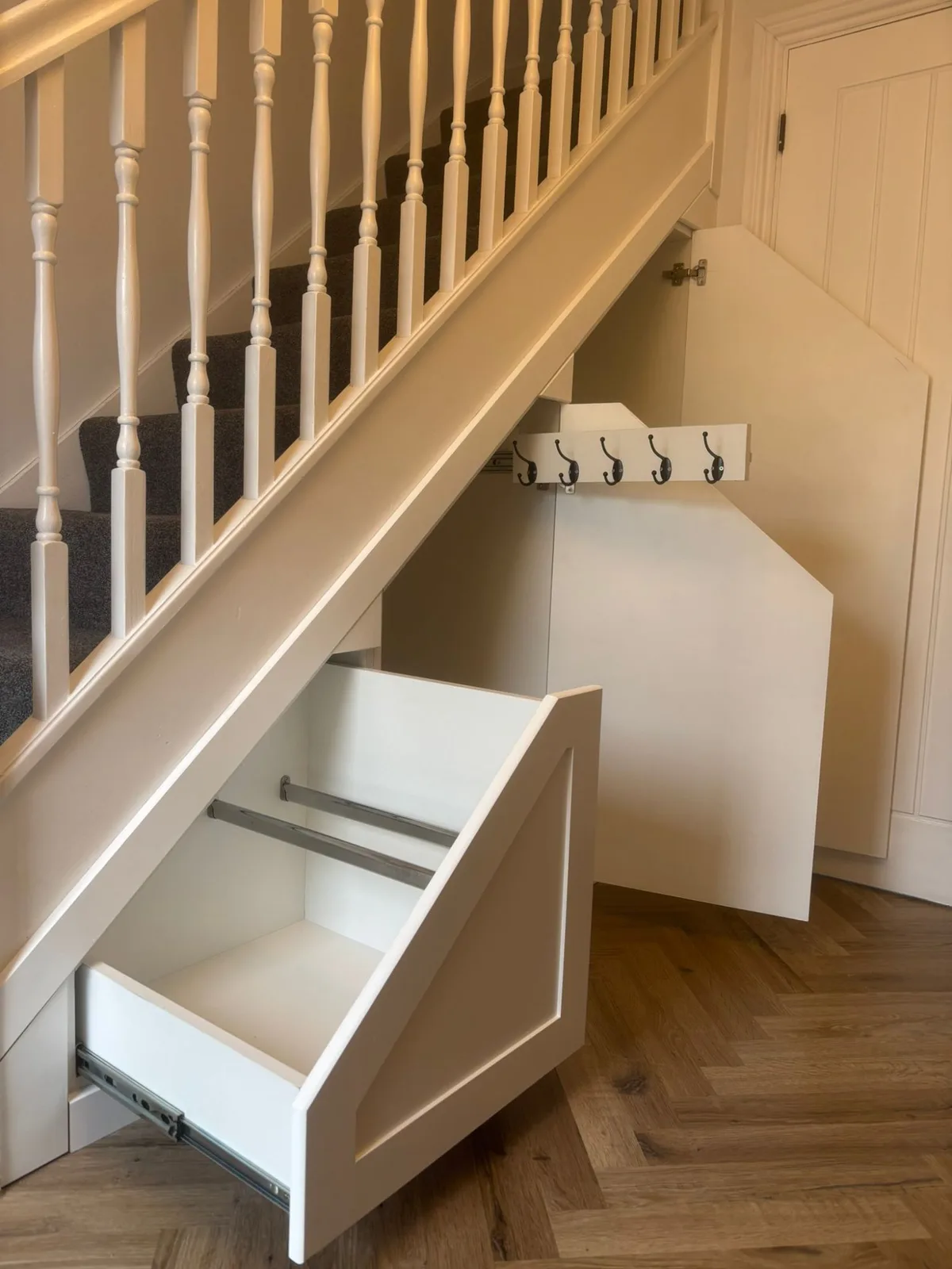 Under-stair pull-out storage open, showing coat hooks and shelving